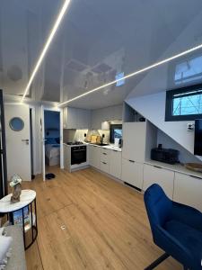 a large kitchen with white cabinets and a blue chair at Hausboot Nikolai Stralsund in Stralsund