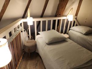 a bedroom with two beds and two lights on the wall at Le Moulin de la Motte Baudoin in Noyers-sur-Cher