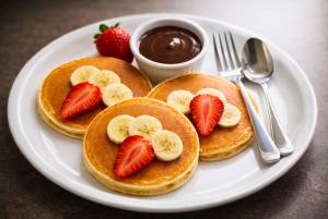 Drei Pfannkuchen mit Erdbeeren und Bananen auf einem weißen Teller in der Unterkunft Hotel Vía Norte Inn - Nuevo - Estacionamiento gratis - Ubicación estratégica in Tuxtla Gutiérrez