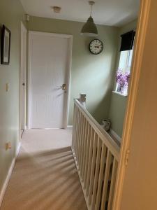 a hallway with a white door and a clock on the wall at The Pudd in Aylesbury