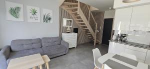 a living room with a gray couch and a kitchen at Aprum Apartments 10C in Pobierowo