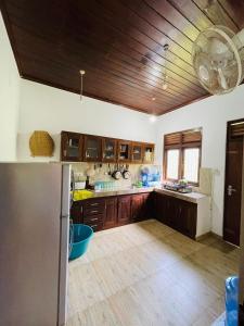 a large kitchen with wooden cabinets and a refrigerator at Hiru Villa in Bentota