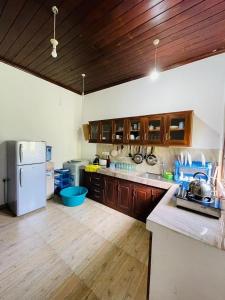 a kitchen with wooden cabinets and a white refrigerator at Hiru Villa in Bentota