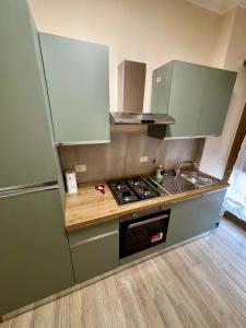 a kitchen with green cabinets and a stove top oven at Grazioso Appartamento Ostia Roma in Lido di Ostia