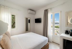 a white bedroom with a bed and a window at Galation in Mikonos