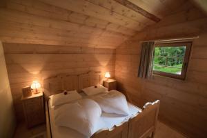 a bed in a wooden room with two lamps on tables at Berghütte Sommerstall in Redagno