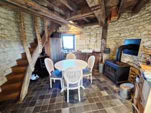 a dining room with a table and chairs and a stove at Le Moulin de la Motte Baudoin in Noyers-sur-Cher