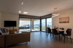 a living room with a couch and a table with chairs at Sun and Sea Apartment - Beachfront, 2 Bedrooms with Sea View & Garden in Paralio Astros