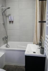 a bathroom with a white tub and a sink at Chocolat Paris, Cozy apartment in Levallois-Perret