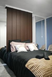 a bedroom with a large bed with black sheets and white pillows at Chocolat Paris, Cozy apartment in Levallois-Perret