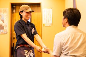 a woman shaking hands with a man in a room at Sun Hotel Kudamatsu in Hanaoka