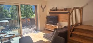 a living room with a television and a balcony at Penthouse Vero I Bergblick I Seenähe I Hallstatt in Obertraun
