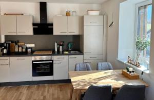 a kitchen with white cabinets and a wooden table at Penthouse Vero I Bergblick I Seenähe I Hallstatt in Obertraun