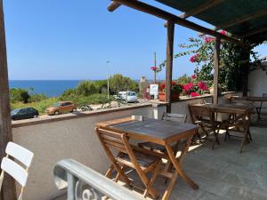 a patio with tables and chairs and a view of the ocean at Andrea E Valentina in S'archittu Cuglieri