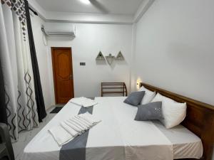 a bedroom with a bed with white sheets and blue pillows at Lethi Family Villa in Negombo