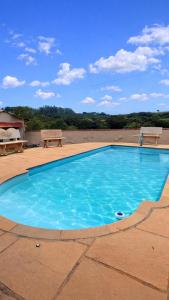 a blue swimming pool on a patio with a bench at Pousada e Camping Caldeirão Furado in São Thomé das Letras