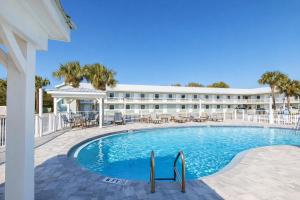 a hotel with a swimming pool and tables and chairs at Destin Inn & Suites in Destin