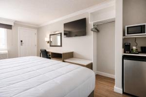 a hotel room with a white bed and a desk at Destin Inn & Suites in Destin