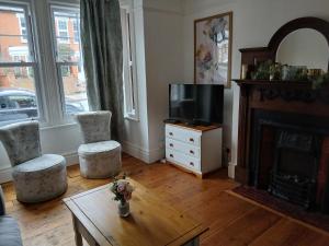 a living room with a fireplace and two chairs and a tv at Spacious 4 Bedroom House, Garden, Nr Ipswich Town Centre with hot tub in Ipswich