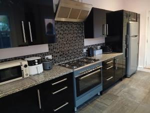 a kitchen with black cabinets and a blue stove top oven at Spacious 4 Bedroom House, Garden, Nr Ipswich Town Centre with hot tub in Ipswich