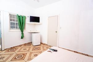 a room with a bed and a television and a window at Hotel&Hostal Trinidad in La Ceiba
