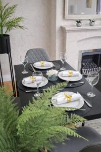 a black table with plates and wine glasses on it at Rosie House 3 bedroom House in Sandbach with Parking in Sandbach