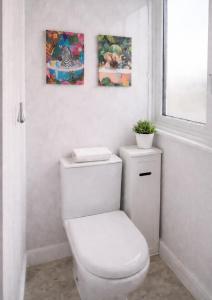 a white toilet in a bathroom with two paintings on the wall at Rosie House 3 bedroom House in Sandbach with Parking in Sandbach +26 photos