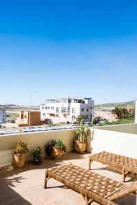 ein Balkon mit zwei Bänken und Blick auf den Strand in der Unterkunft Ims'Chill Hotel in Imsouane