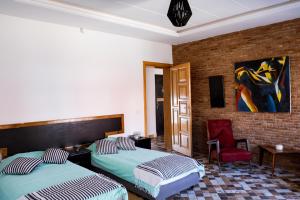 ein Schlafzimmer mit zwei Betten und einem roten Stuhl in der Unterkunft Ims'Chill Hotel in Imsouane