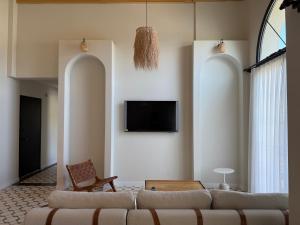 a living room with a couch and a tv on the wall at Kırmızı Bağ Resort in Kuscular