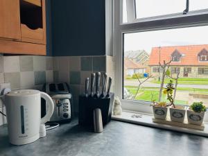 a kitchen counter with a window with utensils at Brada View - Bamburgh, Northumberland in Bamburgh