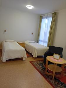 a room with two beds and a table and a chair at Birgittaklosteret i Trondheim in Trondheim