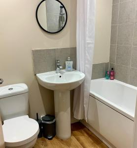 a bathroom with a sink and a toilet and a mirror at 1BR Flat By Cozy Quarters Property Management Short Term Rental Hartlepool Near Marina Views in Hartlepool