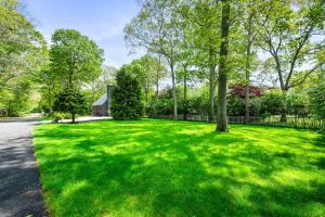 a green yard with trees and a house at BlackBerry - Private home with Jacuzzi year-around in East Hampton