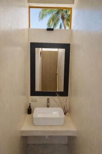 a bathroom with a sink and a mirror at Frequency Hostel beachfront in El Cuyo