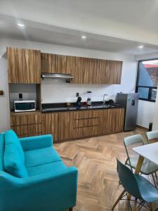 a living room with a blue couch and a kitchen at Downtown Historic Area Modern and Comfortable in Puebla