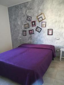 a bedroom with a purple bed with pictures on the wall at Nicla 3 in Fiorino +17 photos