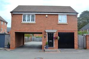 a red brick house with a garage and a driveway at Cathedral Coach House - Lichfield in Lichfield
