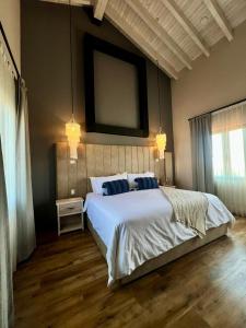 ein Schlafzimmer mit einem großen weißen Bett und zwei blauen Kissen in der Unterkunft Suites Campestres Montebello in Bernal