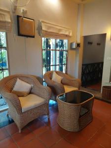 a living room with wicker chairs and a table at Baan Rim Tarn B&B in Takua Pa