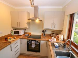 a kitchen with white cabinets and a sink at 48 Edenbank Road in Cupar +17 photos