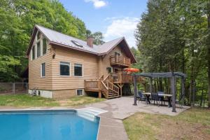 a log house with a deck and a pool at Modern Cottage Laurentians Private Pool & Nature in Brownsburg