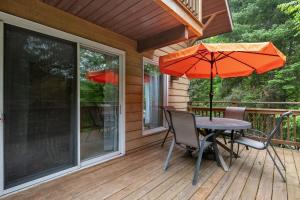 a table and chairs on a deck with an umbrella at Modern Cottage Laurentians Private Pool & Nature in Brownsburg