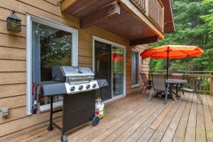 a grill on a deck with a table and an umbrella at Modern Cottage Laurentians Private Pool & Nature in Brownsburg