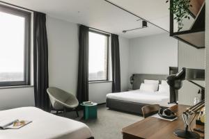 a hotel room with two beds and a desk at The Social Hub Eindhoven in Eindhoven