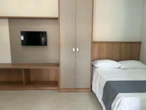a bedroom with a bed and a cabinet with a tv at Studio J&C 01 in Primavera do Leste