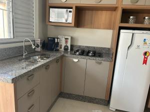 a kitchen with a white refrigerator and a sink at Studio J&C 01 in Primavera do Leste