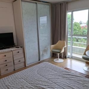 a bedroom with a bed and a television and a chair at Quarto aconchegante in Curitiba