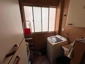a small bathroom with a washing machine and a window at Ap decorado Setor Bueno in Água Boa