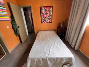 a small bed in a room with an orange wall at Ap decorado Setor Bueno in Água Boa